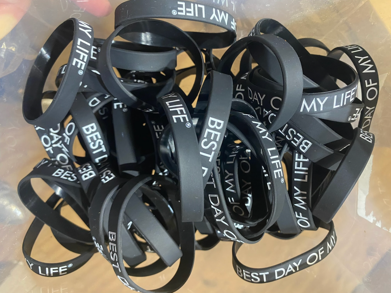 pile of black wristbands with best day of my life written in white